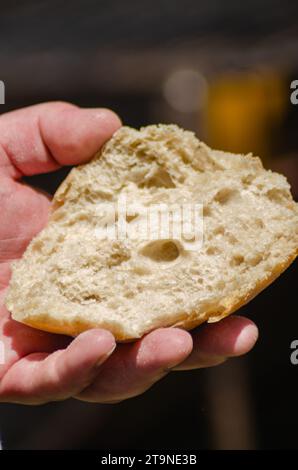 Halten Sie ein Stück Brot in der Hand, um ein Bifana zu machen, ein typisch portugiesisches Fleischsandwich. Stockfoto