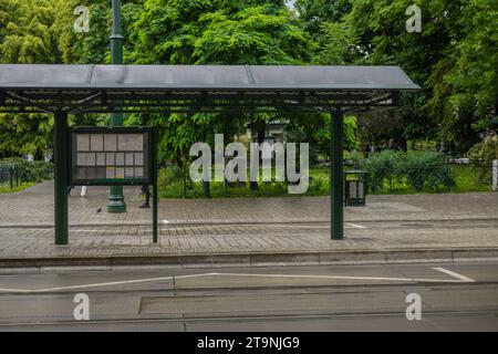 Typische Bus- oder Straßenbahnhaltestelle in grüner Farbe mit Dach, wie sie an nassen Tagen in Krakau, Polen, zu sehen ist. Seitenansicht eines Busbahnhofs. Stockfoto