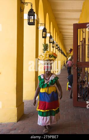 Eine Palenquera, oder Obstverkäufer aus der Stadt Palenque, blitzt mit ihrem bunten Outfit in Cartagena de Indias, Kolumbien, durch die Straßen Stockfoto