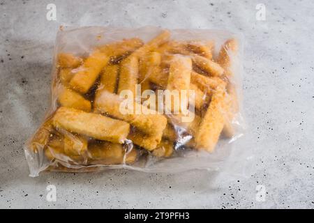 Beutel mit gefrorenen panierten Fischstäbchen aus nächster Nähe auf grauem Steinhintergrund Stockfoto