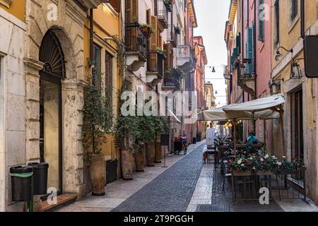 Gebäude mit Topfpflanzen in Verona, Italien. Charmante, alte verwitterte Fassade mit Fensterläden Stockfoto