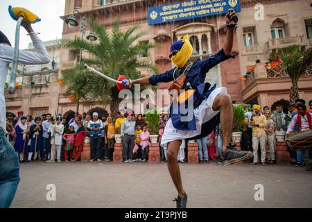 Neu-Delhi, Indien. November 2023. Junge Sikhs zeigen ihre Kampfkunst bei der langen und farbenfrohen Nagar Kirtan Prozession in der Nähe von Shish Ganj Gurudwara am Tag vor dem Prakash Parv (554. Geburtstag von Sri Guru Nanak Dev Ji) in Alt-Delhi. Die Feier des Geburtstages von Guru Nanak Dev Ji ist mit verschiedenen Aktivitäten und Veranstaltungen innerhalb der Sikh-Gemeinschaft gekennzeichnet. Gurdwaras (Sikh-Tempel) werden dekoriert, und spezielle Gebete, Kirtan (Andachtsgesang) und Prozessionen werden von Sikh organisiert. Quelle: SOPA Images Limited/Alamy Live News Stockfoto