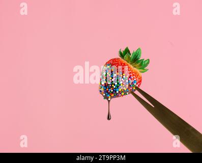 Erdbeere mit Schokoladenüberzug und Streuseln auf einer Gabel. Stockfoto
