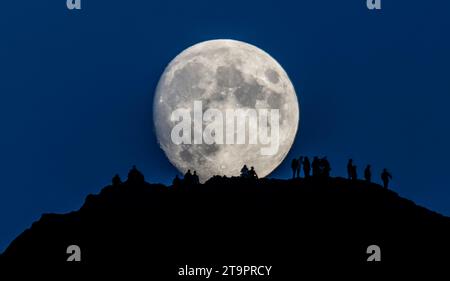 Wetter, Nachrichten, Arthurs Seat, Holyrood Park, Edinburgh, UK. November 2023. „Moonwalkers“. Versammeln Sie sich an einem kühlen frühen Abend auf dem Arthurs Seat im Zentrum von Edinburgh, um zu beobachten, wie der nahe Full Beaver Moon über ihnen aufsteigt. Von der Website der Royal Museums Grenwich: „Es gibt Uneinigkeit über den Ursprung des Bibermondnamens im November. Einige sagen, dass er von den Indianern stammt, die in diesem Monat Biberfallen gesetzt haben, während andere sagen, dass der Name von der starken Aktivität der Biber stammt, die ihre Winterdämme bauen. Ein anderer Name ist der Frostmond." Bildnachweis: phil wilkinson/Alamy Live News Stockfoto