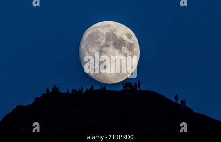 Wetter, Nachrichten, Arthurs Seat, Holyrood Park, Edinburgh, UK. November 2023. „Moonwalkers“. Versammeln Sie sich an einem kühlen frühen Abend auf dem Arthurs Seat im Zentrum von Edinburgh, um zu beobachten, wie der nahe Full Beaver Moon über ihnen aufsteigt. Von der Website der Royal Museums Grenwich: „Es gibt Uneinigkeit über den Ursprung des Bibermondnamens im November. Einige sagen, dass er von den Indianern stammt, die in diesem Monat Biberfallen gesetzt haben, während andere sagen, dass der Name von der starken Aktivität der Biber stammt, die ihre Winterdämme bauen. Ein anderer Name ist der Frostmond." Bildnachweis: phil wilkinson/Alamy Live News Stockfoto