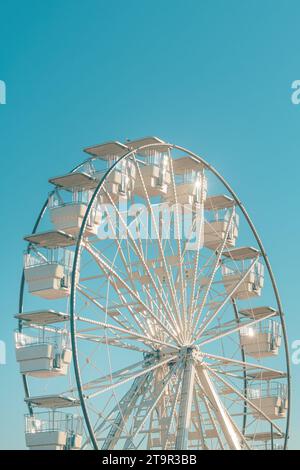 Das riesige weiße Riesenrad für Panoramablick im Vergnügungspark ist eine beliebte unterhaltsame Fahrt, die am hellen, sonnigen Tag am blauen Himmel geschossen wird Stockfoto