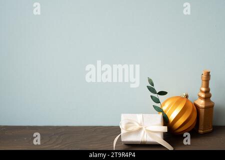 Weihnachtsdekoration Ornament goldene Kugel, Geschenkbox auf Holztisch. Blauer Wandhintergrund Stockfoto