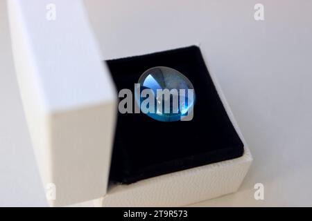 Geöffnete Schmuckschatulle mit blauem Mineralstein auf schwarzem Seidensamtpolster Stockfoto