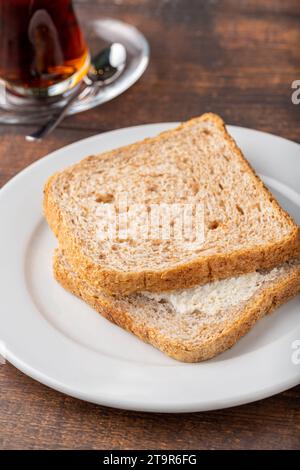 Frischkäse-Sandwich auf weißem Porzellanteller auf Holztisch Stockfoto