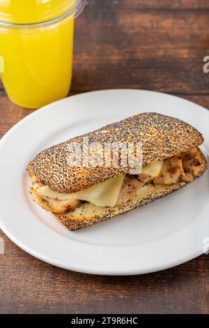 Sandwich mit Cheddar-Käse und Hühnchen auf weißem Porzellanteller auf Holztisch Stockfoto