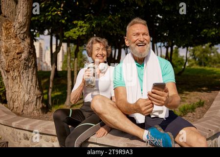 Glückliches überglücktes älteres Ehepaar, das den sonnigen Tag nach dem Joggen genießt Stockfoto