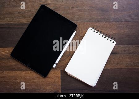 Von oben auf einen Holztisch mit Notizbüchern und einem Stift. Stockfoto
