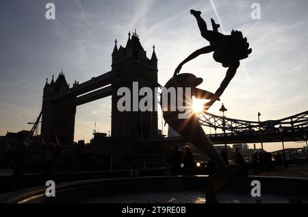 London England - 8. September 2014: Eine Silhouette des Mädchens mit Dolphin Fountain und Tower Bridge bei Sonnenuntergang. Stockfoto