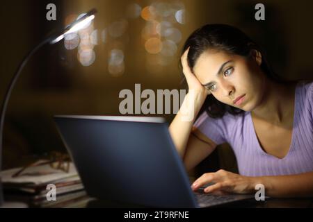 Eine besorgte Frau in der Nacht benutzte einen Laptop und beschwerte sich allein zu Hause Stockfoto