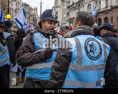 London, Großbritannien. November 2023. Ein Metropolitan-Polizist spricht bei der pro-israelischen Demonstration "Marsch gegen den Antisemitismus" mit einem Freiwilligen-Verwalter, um Geiseln zu unterstützen, die von der Hamas in Gaza genommen wurden. Andy Soloman/Alamy Live News Stockfoto