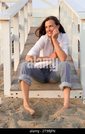 Eine Frau beobachtet den Sonnenuntergang von der Promenade am Hammonasset Beach in Madison, Connecticut. Stockfoto