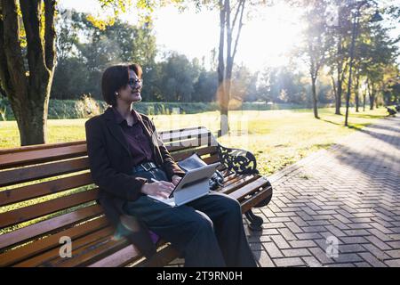 Junge, stilvolle Frau mit Tablet und Kopfhörern im Park Stockfoto