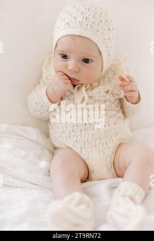 Vorderansicht eines Mädchens, das in neutraler Babykleidung und Motorhaube sitzt Stockfoto