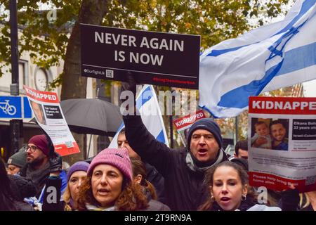 London, Großbritannien. November 2023. Ein Demonstrant hält während der Demonstration ein Schild mit der Aufschrift „nie wieder ist jetzt“. Tausende pro-israelische Demonstranten marschierten in Zentral-London gegen den Antisemitismus und forderten die Freilassung israelischer Geiseln, die von der Hamas in Gaza festgehalten wurden. Quelle: SOPA Images Limited/Alamy Live News Stockfoto