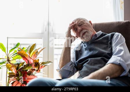 Ein älterer Mann, der zu Hause in einem Sessel schläft Stockfoto