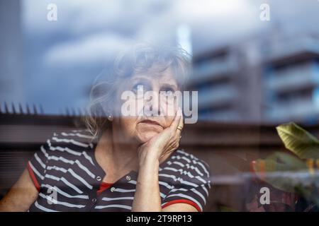 Porträt von senior Frau Blick durch Fenster Stockfoto