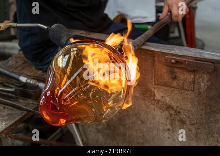 Eine Glasvase, die von einem Glasbläser mit einer Flammenlampe im Glasofen Wave Murano auf der Insel Murano in der Nähe von Venedig in der Veneto Re geformt wird Stockfoto