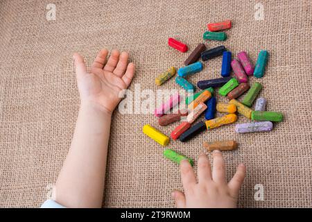 Benutzte Farbstifte und eine Hand für Kleinkinder auf Leinwand Stockfoto