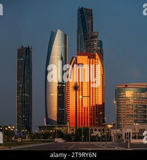 Blick auf die Skyline von Abu Dhabi bei Sonnenuntergang in den Vereinigten Arabischen Emiraten, mit den Etihad-Türmen, die bei Sonnenuntergang leuchten Stockfoto