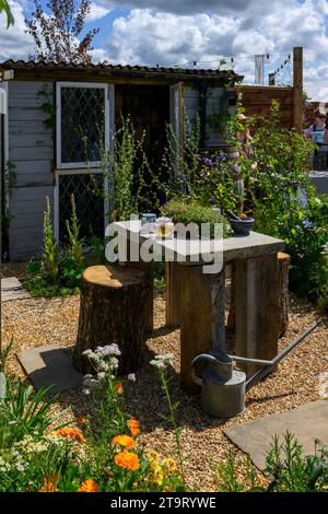 Eintritt zum Gartenwettbewerb „The Apothecary Terrace Garden“ (umgedrehte Baumstämme als Sitze, Holzschuppen) – RHS Tatton Park Flower Show 2023, Cheshire England UK. Stockfoto