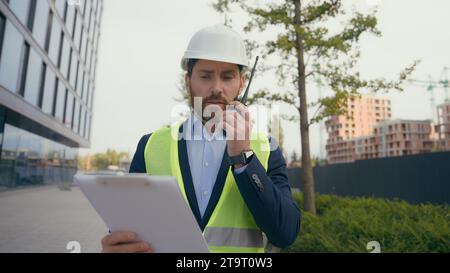 Kaukasischer professioneller Bauarbeiter Arbeiter im Walkie Talkie Baumeister mittleren Alters in Hard hat Talk Remote Radio man Architekt Ingenieur Stockfoto