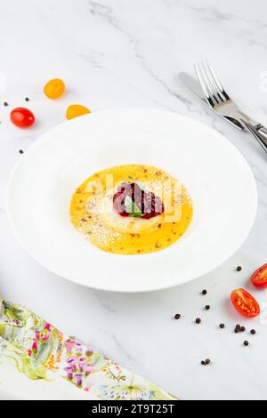 Ingwerkürbissuppe mit Knödeln und Beeren. Weißer Hintergrund, Seitenansicht Stockfoto