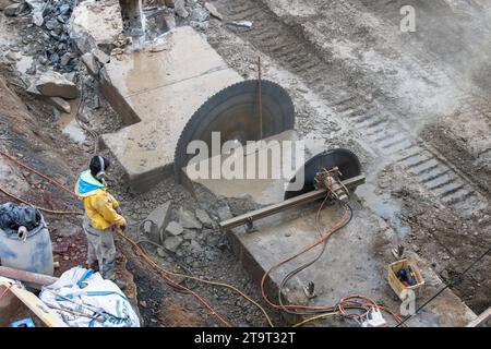 Abriss eines Betonsockels mit einer Betonsäge und einem Bagger am Rheinufer, Köln, Deutschland. Abriss eines Betonsockels mit Betonsae Stockfoto