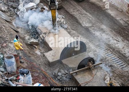 Abriss eines Betonsockels mit einer Betonsäge und einem Bagger am Rheinufer, Köln, Deutschland. Abriss eines Betonsockels mit Betonsae Stockfoto