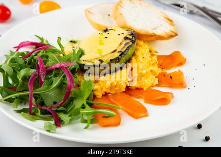 Eine Mischung aus Lachs, Rucolasalat, Weißbrot und gebackener Avocado mit seitlichem Blick auf den Käse Stockfoto