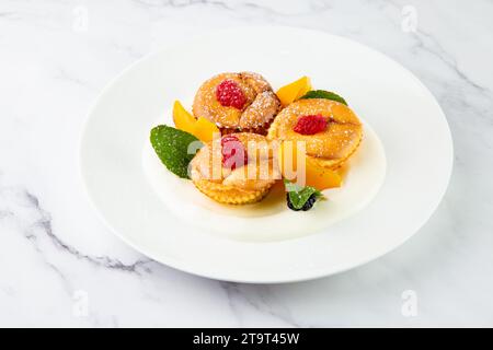 Muffins mit Pfirsich, Himbeere, schwarzer Beere und Minze mit Puderzucker, Seitenansicht Stockfoto