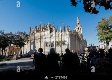 Leute, die auf einer Bank im Schatten sitzen und auf die Kathedrale von Sevilla und den Glockenturm Giralda blicken, Sevilla, Andalusien, Spanien. Europa. Stockfoto