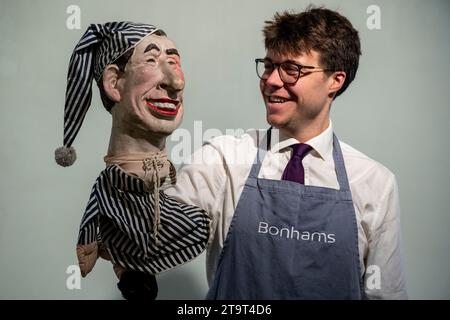 London, Großbritannien. 27. November 2023. Ein Techniker mit einer „Handpuppe von (Prince) Charles in Nachtwäsche“ von Spitting Image, ca. 1980er Jahre, (800 £ - 1.200 £) bei einer Vorschau auf den Rock, Pop & Film-Verkauf von Bonhams. Der Verkauf findet am 29. November in den Bonhams Knightsbridge Galeries statt. Quelle: Stephen Chung / Alamy Live News Stockfoto