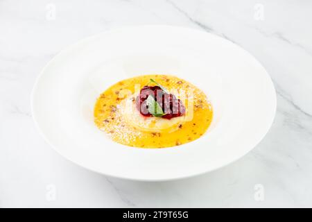 Ingwerkürbissuppe mit Knödeln und Beeren. Weißer Hintergrund, Seitenansicht Stockfoto