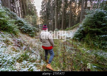 Frau mit Wackelhut, die im herbstlichen Wald zur Linse zurücksteht Stockfoto