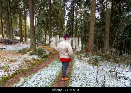 Frau mit Wackelhut, die im herbstlichen Wald zur Linse zurücksteht Stockfoto