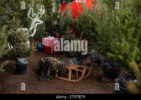 Unter dem Weihnachtsbaummarkt im Innenhof befinden sich große Holzschlitten. Rasendekoration für das neue Jahr mit Geschenken, Girlanden, geführtem Hirsch, Jin Stockfoto