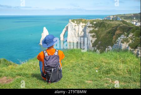 Ein Mann sitzt auf der Klippe mit Blick auf die Klippen im Hintergrund in La Falaise d'Amont, Frankreich Stockfoto