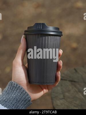 Eine Frau, die einen Papierkaffeetasse zum Mitnehmen in der Hand hält. Stockfoto