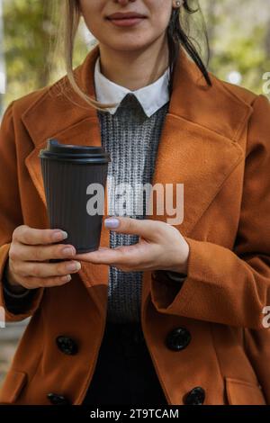 Frau, die einen Papierkaffeetasse in der Hand hält. Stockfoto