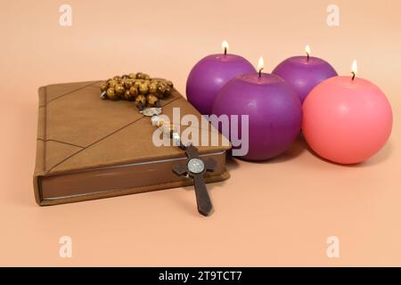 Vier Adventskerzen, Rosenkranz und Gebetsbuch. Adventskonzept. Stockfoto