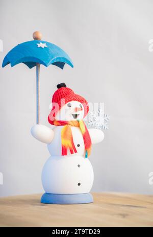 Dekorativer Schneemann mit Regenschirm mit rotem Hut und Schal. Stockfoto