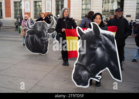 Mehrere Personen zeigen Fahnen und Banner mit Bildern von Stieren während einer Demonstration gegen Stierkämpfe in der Puerta del Sol am 27. November 2023 i. Stockfoto