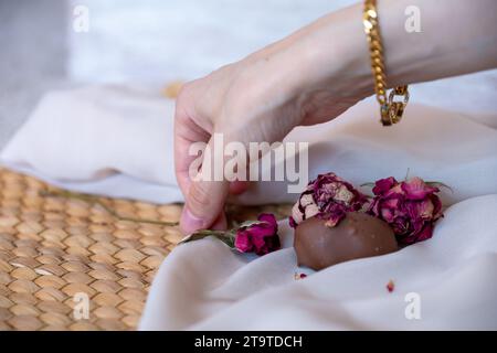 Schokoladenstücke mit eleganten Blumen und Rosen auf rosa und weißem Hintergrund. Romantisches Konzept mit Mock-up-Raum für individuelle Anpassungen. Ideen für Valenti Stockfoto