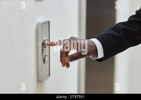 Nahaufnahme des Schwarzen Mannes, der mit dem Zeigefinger den Lift-up-Knopf im Bürogebäude drückt, Kopierraum Stockfoto