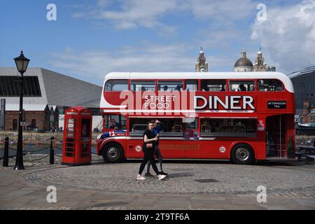 Touristen laufen vorbei am Red Double-Decker Bus, der in Street Food Diner, Food Truck oder Restaurant an der Waterfront oder Pier Head Liverpool England UK umgewandelt wurde Stockfoto